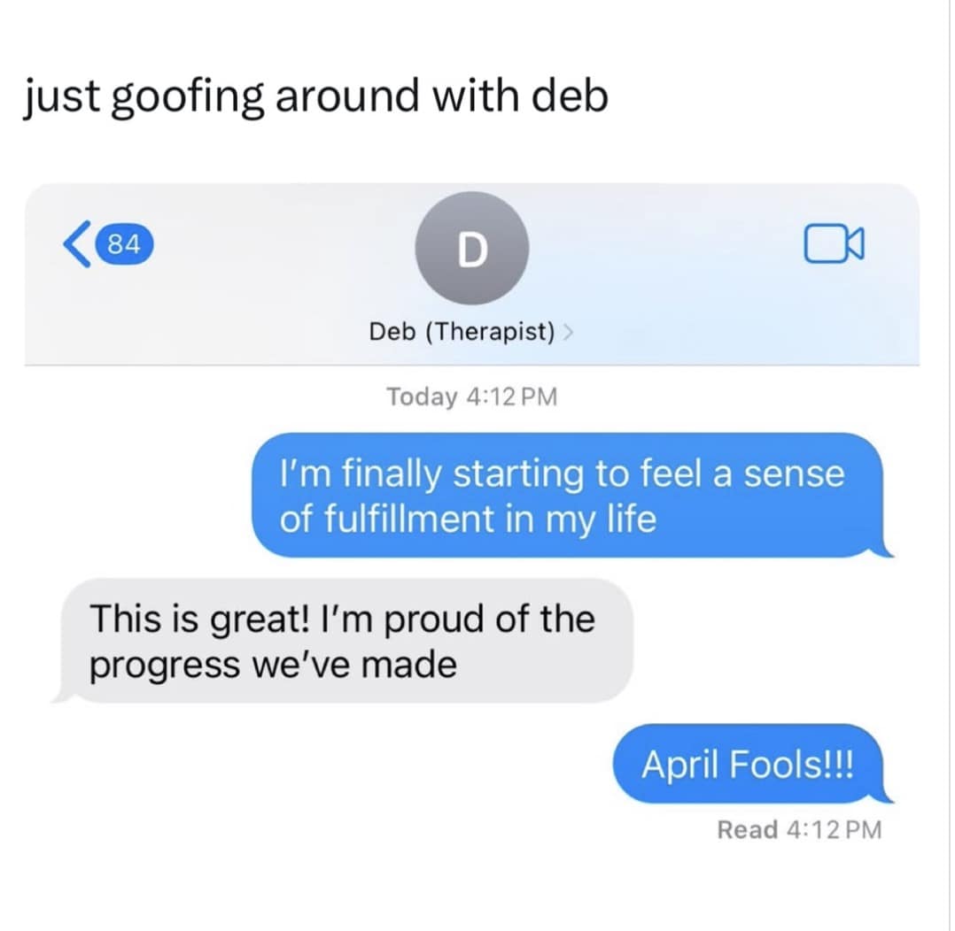 A self-deprecating 2026 April Fools meme showing a text exchange with "Deb (Therapist)." The user tells her they are finally starting to feel a sense of fulfillment in life. After the therapist expresses how proud she is of the progress, the user delivers a crushing "April Fools!!!" punchline.
