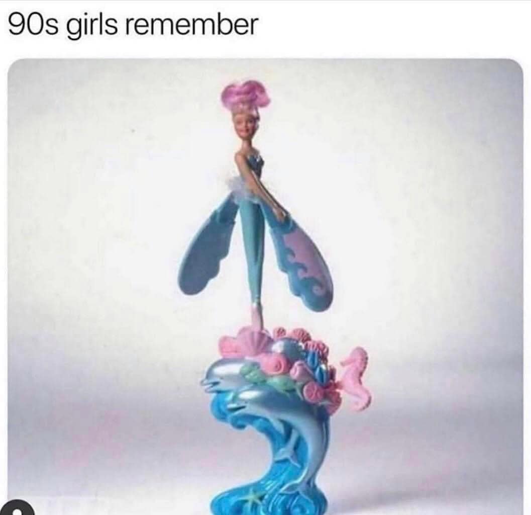 A nostalgia meme showcasing the iconic "Sky Dancer" toy—a pink-haired doll on a blue dolphin base that spins into the air—with the simple declaration: "90s girls remember."