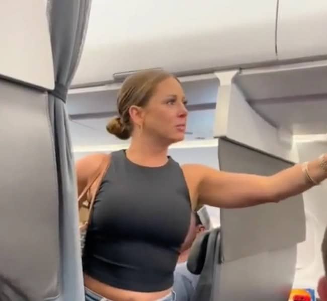 A woman on an airplane looking distressed, referencing the famous "not real" viral video.