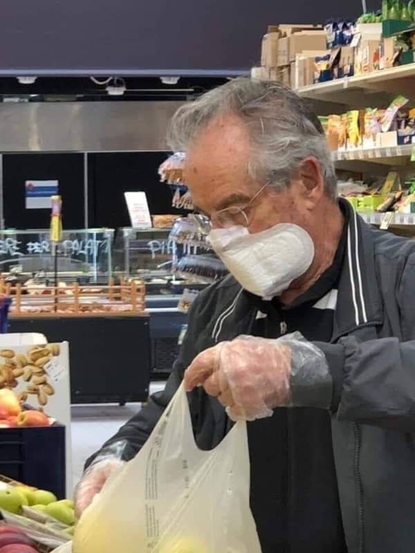 Man in a grocery store wearing a feminine hygiene pad as a makeshift face mask and plastic bags.