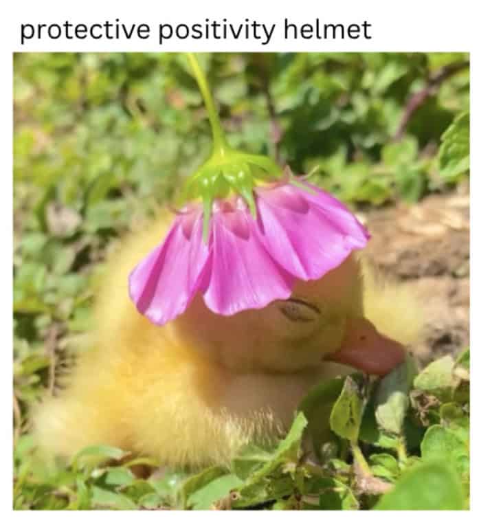 A yellow duckling sleeping peacefully in grass while wearing a pink flower as a protective helmet.