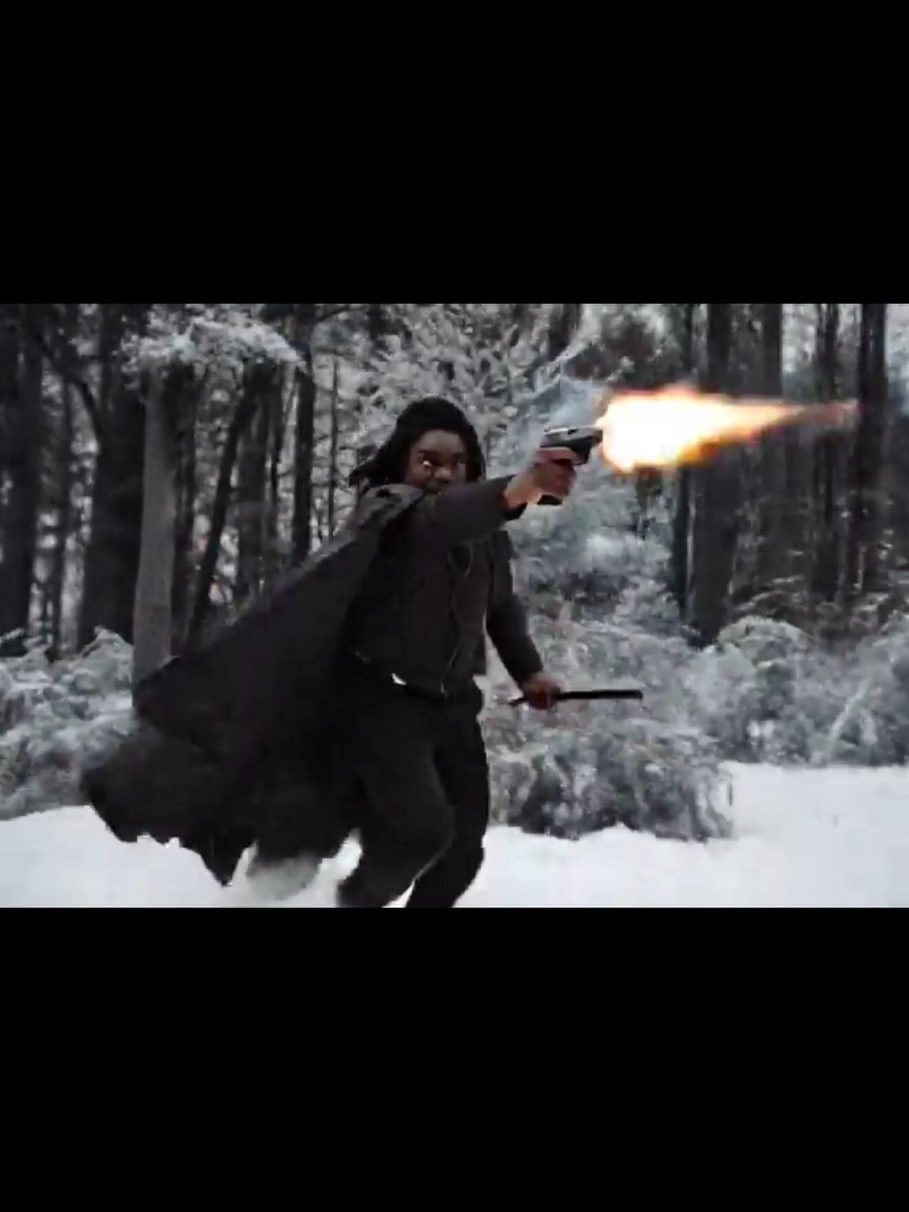 An action-packed new snape meme showing the actor edited into a snowy forest scene. Instead of a wand, he is aggressively dual-wielding, firing a semi-automatic handgun that emits a large muzzle flash while holding a blade in his other hand.