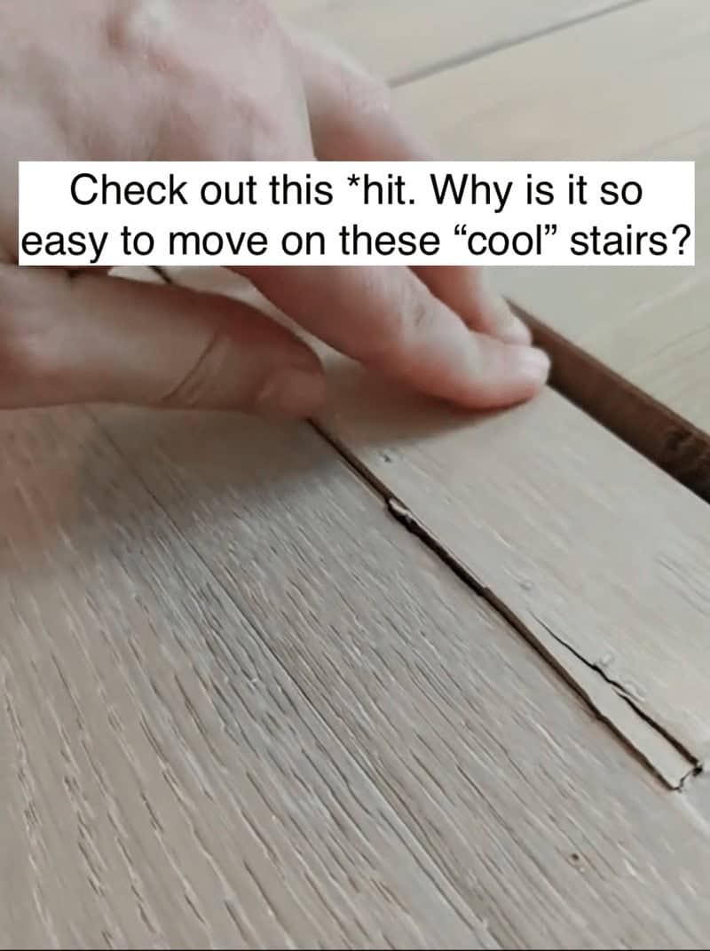 Fingers peeling up loose wood flooring on stairs illustrating poor craftsmanship in a luxury home.