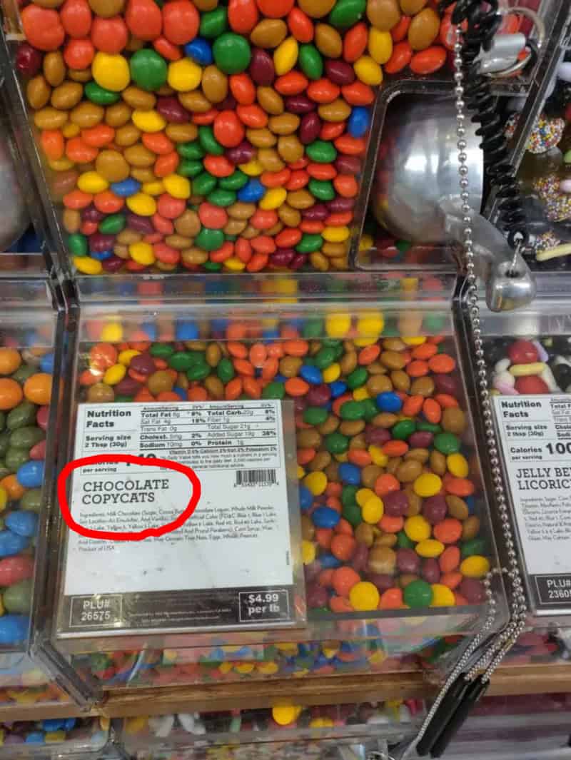 Gumball machine dispenser labeled Chocolate Copycats filled with colorful candy coated chocolate pieces.