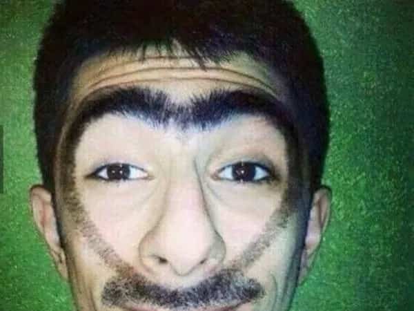 Man with a singular continuous eyebrow line connecting to his sideburns and mustache.
