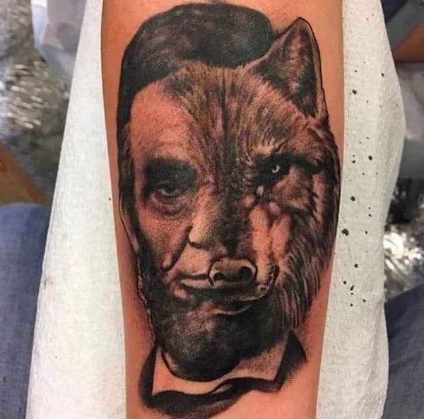 Tattoo of Abraham Lincoln's face blended with a realistic wolf head on an inner forearm.