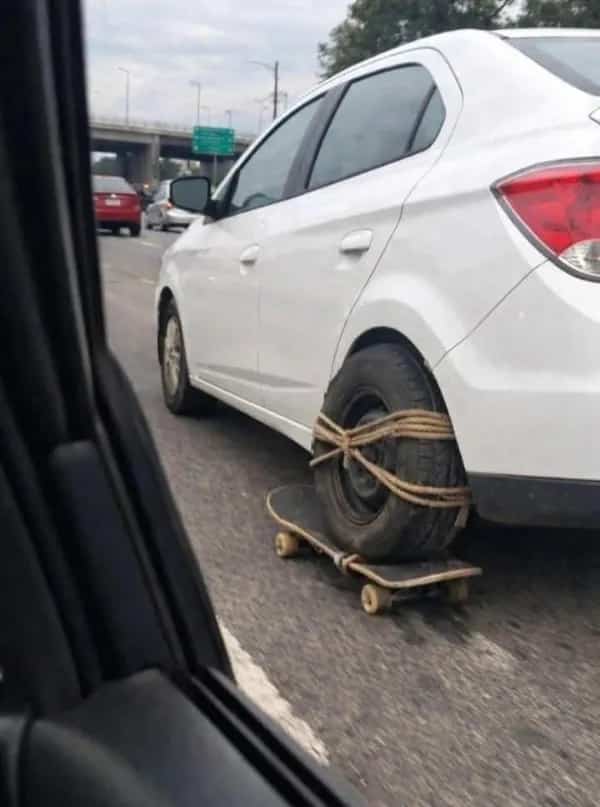 Car drives with tire strapped to skateboard as makeshift wheel, funny memes