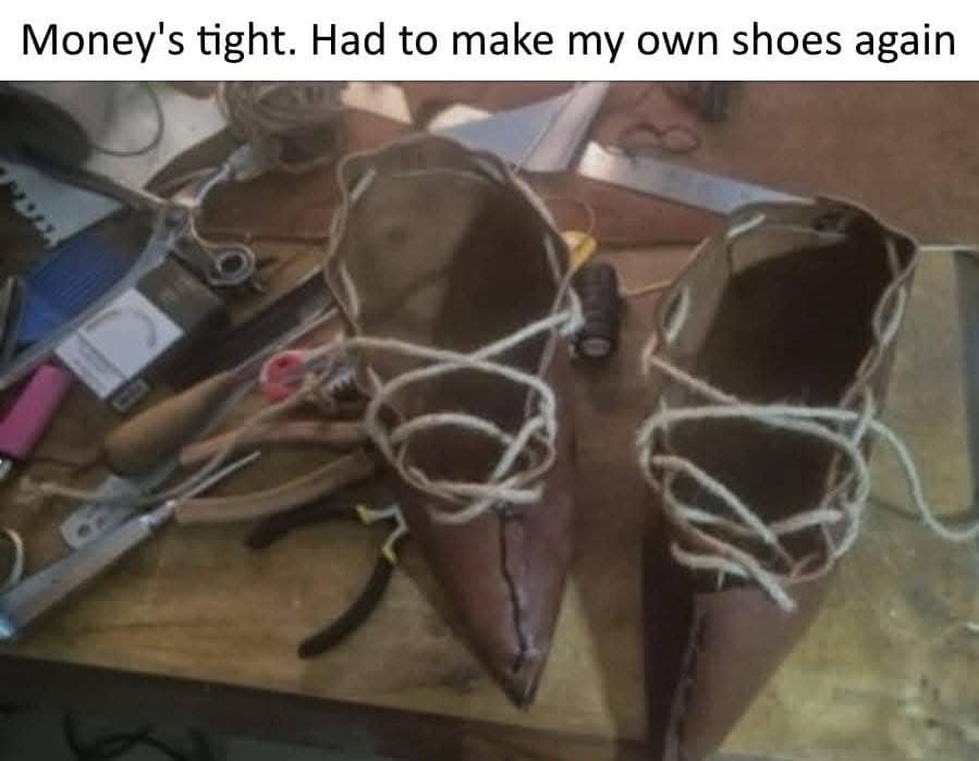 Handmade leather shoes with pointed toes on a workbench with a joke about money being tight.