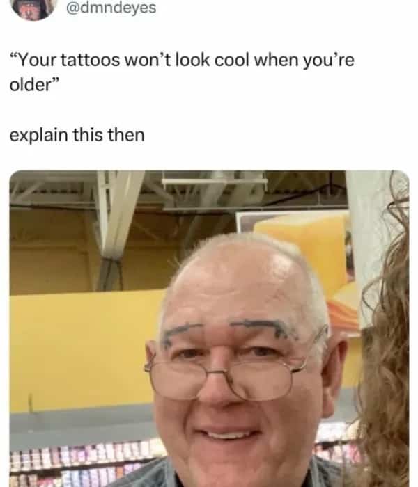 A man smiling with two small handgun tattoos positioned above his eyes where his eyebrows would be.