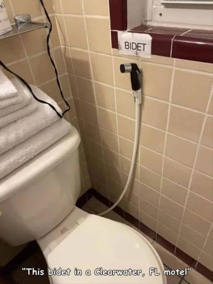 Toilet in a Florida motel featuring a kitchen sink sprayer labeled as a makeshift bidet.