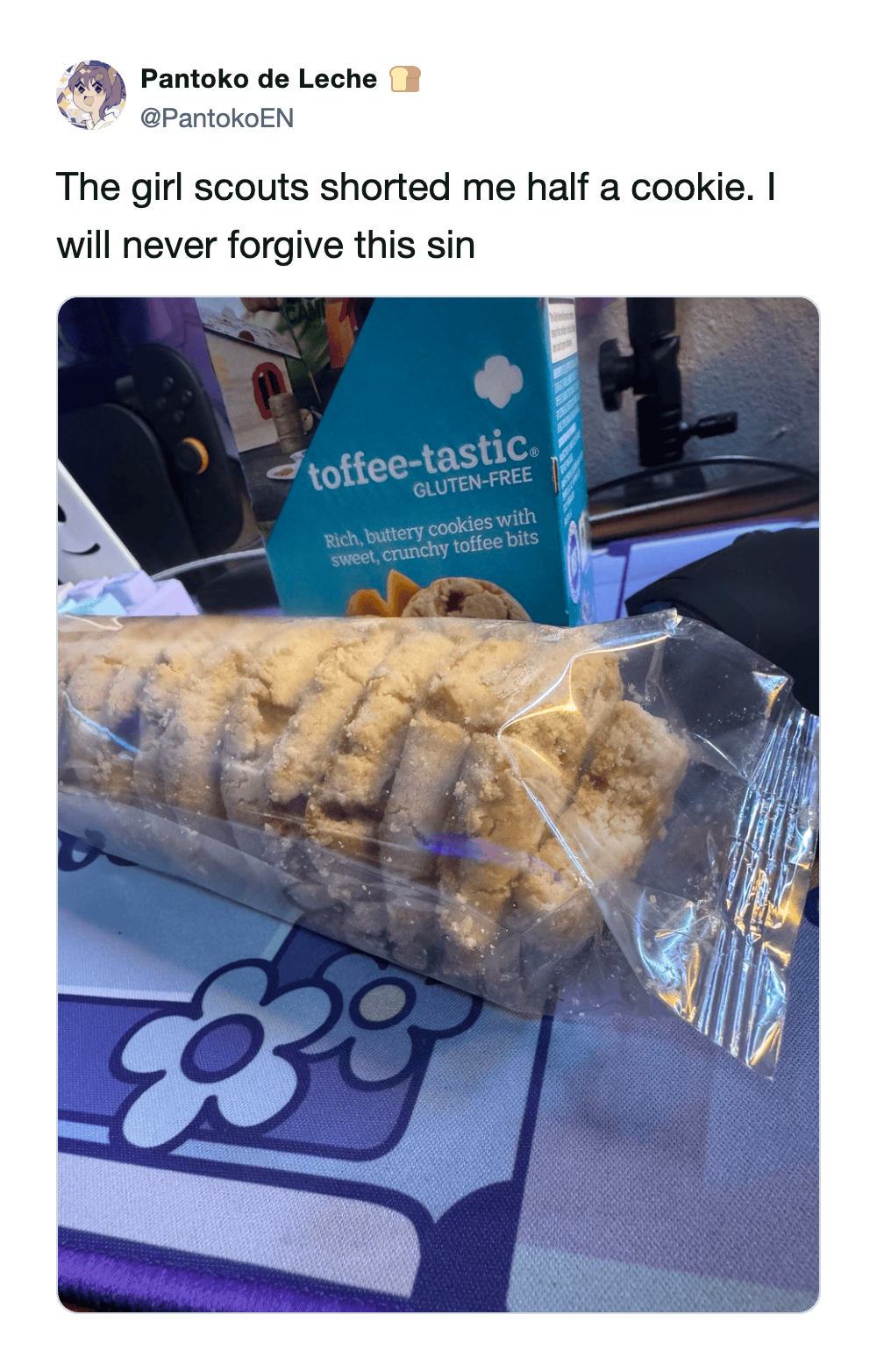 A deeply dramatic manufacturing error girl scout cookie meme showing a sealed plastic sleeve of Toffee-tastics that is missing exactly half of the end cookie, with the user jokingly declaring they will never forgive this sin.