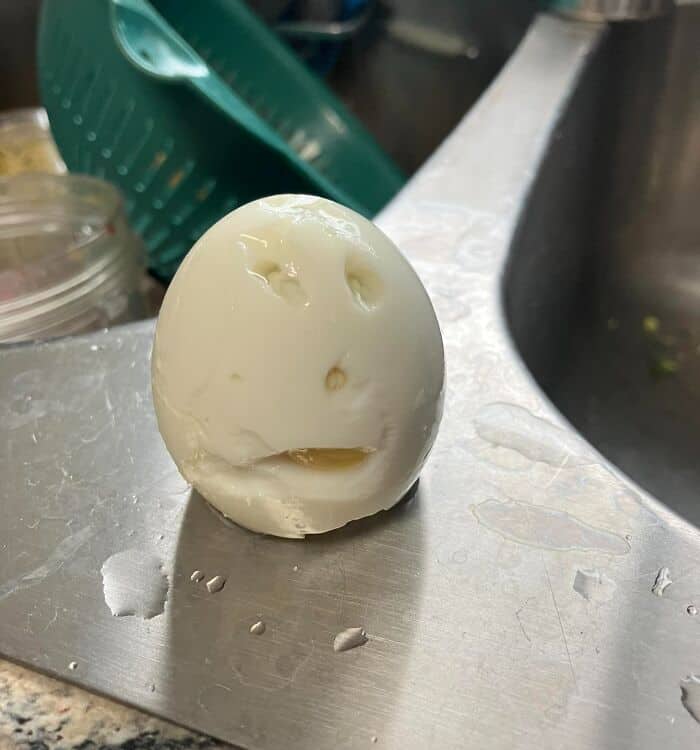 distressed entry of inanimate objects with faces featuring a poorly peeled hard-boiled egg on a sink, where the torn egg whites form a dramatic, wailing facial expression.