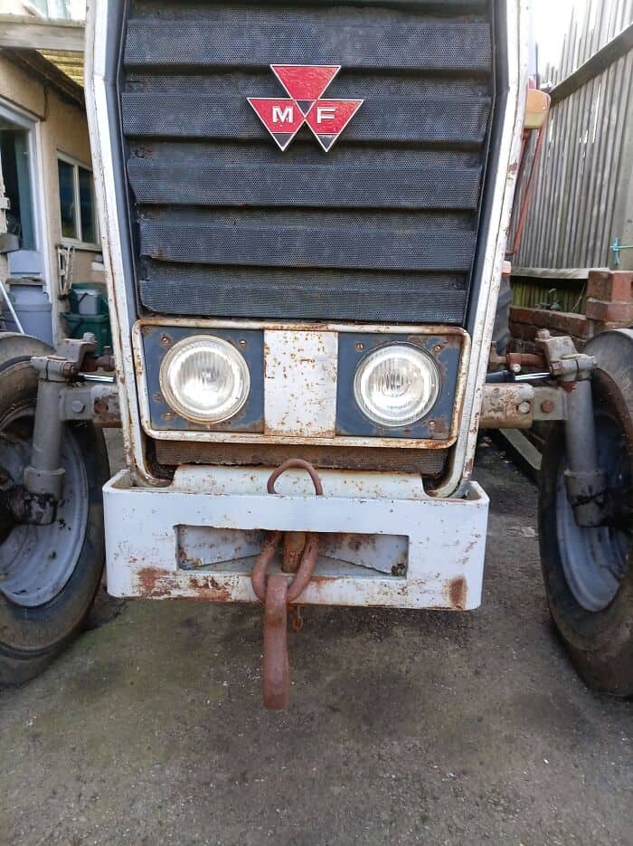 A rustic, mechanical example of inanimate objects with faces showing the front grill of an old, weathered Massey Ferguson tractor, where the round headlights give it a stoic, tired, and nostalgic expression.