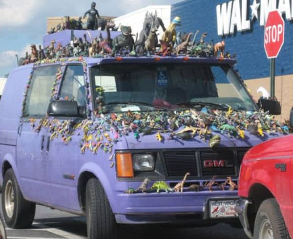 Purple GMC van parked at Walmart with hundreds of toy dinosaurs glued to the exterior.