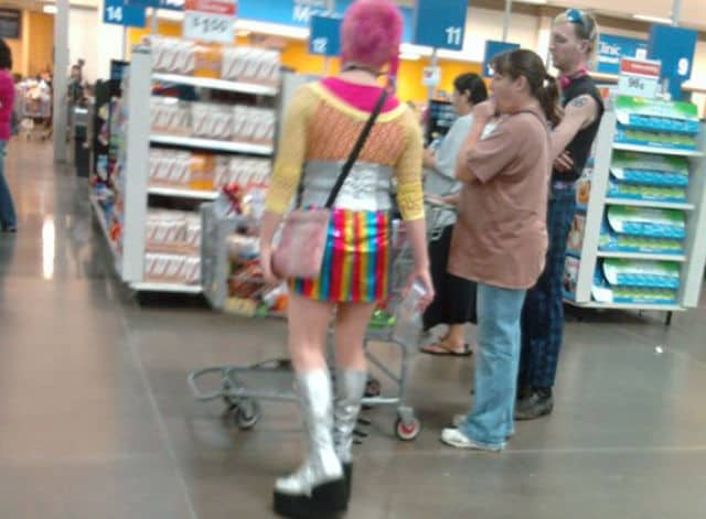 Shopper wearing a rainbow mini skirt, silver platform boots, and a shiny silver corset belt.