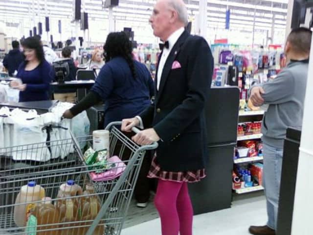 Man in a formal tuxedo jacket and bowtie paired with pink leggings and plaid skirt.