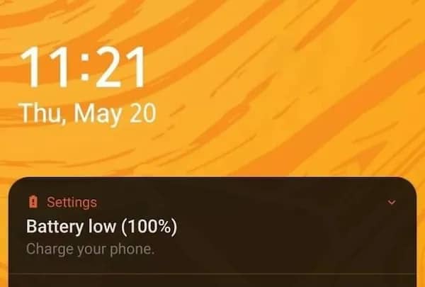 Smartphone lock screen displaying a low battery notification despite the charge level being at 100%.