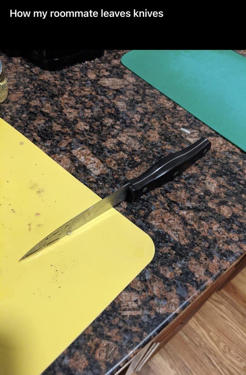 A dangerous habit from one of the worst roommates. A sharp kitchen knife has been left balanced precariously on the very edge of a brown granite countertop, with half the blade hanging over the floor, just waiting to fall.