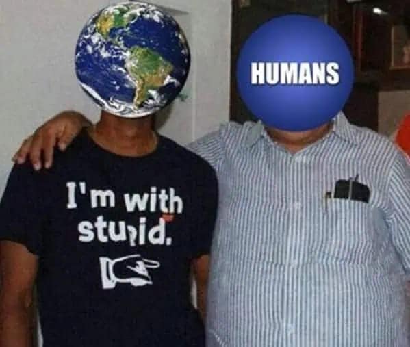 A blunt 2026 Earth Day meme featuring two men side-by-side. The man on the left has an Earth globe for a head and wears a black shirt that says I'm with stupid, with a finger pointing toward the man on the right, whose head is a blue circle labeled HUMANS.