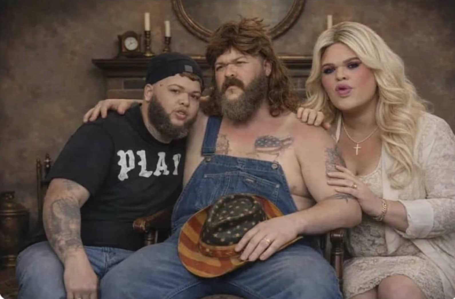 Family portrait featuring a man in overalls with a mullet, flanked by two blonde individuals.