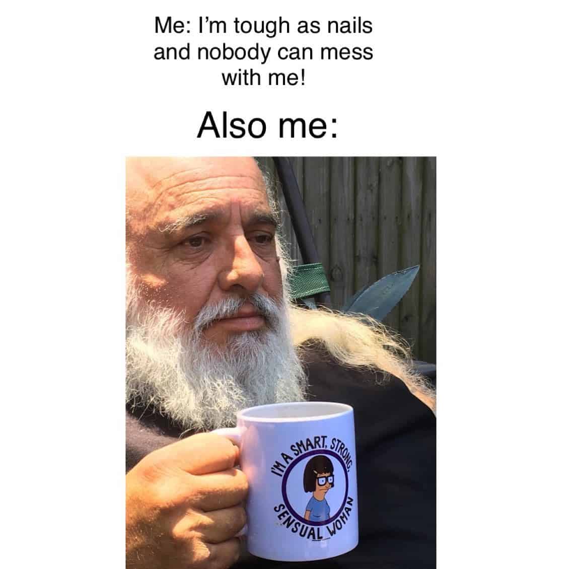 An older, bearded man holds a mug featuring Tina Belcher in this Bobs Burgers meme about internal versus external identity. The mug’s "Smart, Strong, Sensual Woman" quote subverts the man’s tough exterior to reveal his true, awkward soul.