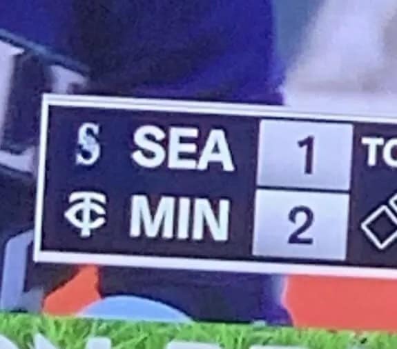 A close-up of a baseball score bug from a game between the Seattle Mariners and the Minnesota Twins. The abbreviations for the teams are placed together to accidentally spell "SEA MIN," a phonetic spelling of a reproductive fluid.
