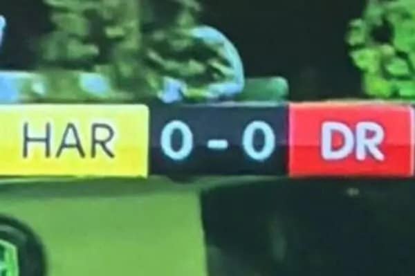 A funny sports graphic on a scoreboard showing the matchup "HAR" vs "DR" at a 0-0 score, accidentally creating the word "HARDER" across the screen in bold white letters.