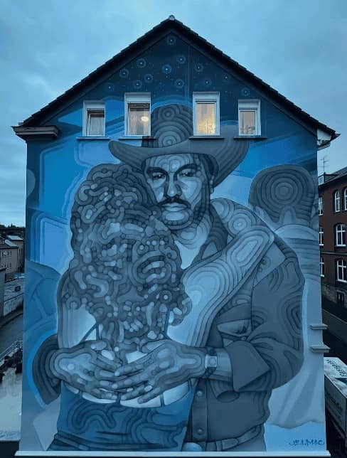 A massive monochromatic mural in shades of blue and grey, covering the side of a multi-story home. The artist used a unique "topographical" line style—resembling fingerprints or wood grain—to depict an intimate embrace between a man in a cowboy hat and a woman, creating a sense of fluid, rhythmic movement across the architecture.