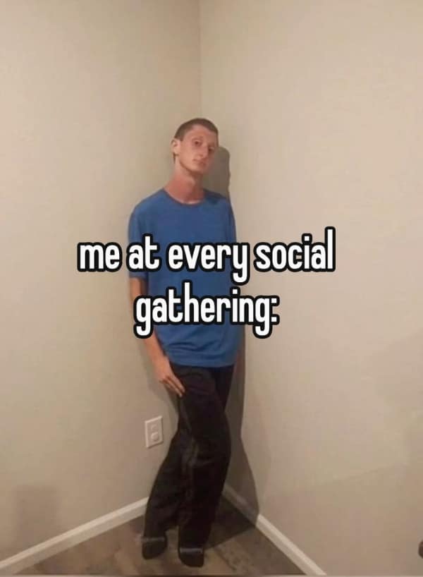 An awkward anxiety meme showing a man leaning stiffly and uncomfortably into the corner of a room. The caption reads: "me at every social gathering," capturing the desperate need to blend into the architecture.