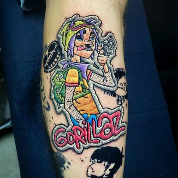 Colorful embroidery style tattoo of a Gorillaz character that looks like a textured fabric patch.