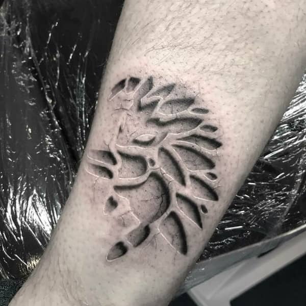 Hyper-realistic 3D tattoo on an arm that looks like carved stone or recessed skin patterns.