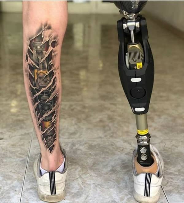 Creative biomechanical tattoo on a leg made to look like internal machinery matching a prosthetic leg.