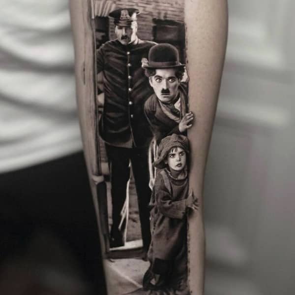 Incredibly detailed black and grey portrait tattoo of Charlie Chaplin and a child peeking around a corner.