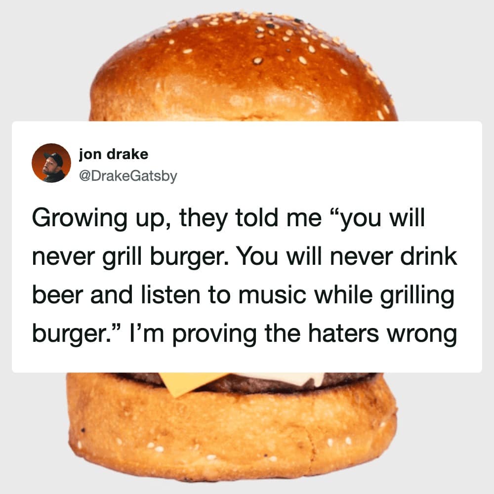 An aspirational bbq meme featuring a massive, sesame-seed bun cheeseburger. The tweet from jon drake ironically describes a childhood where "haters" told him he'd never grill burgers or drink beer, and he is now proudly proving them wrong.