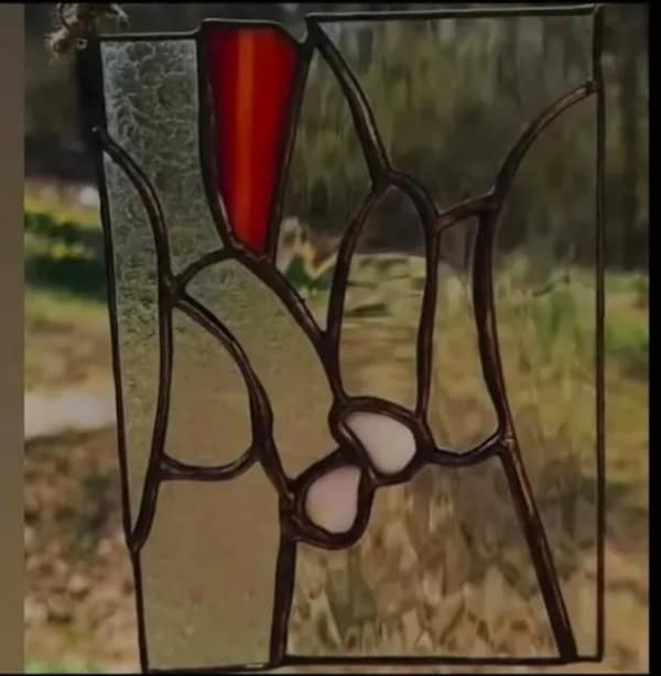 A cleverly deceptive blursed image of a stained glass panel. While intended to be an abstract landscape or perhaps a hand-holding scene, the specific arrangement of lead lines and colored glass creates a very distinct and unfortunate phallic shape.