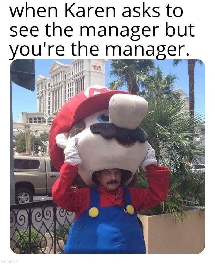 A funny real-life photo acting as a classic meme for retail workers. A man with a thick mustache peeks out of the mouth of a gigantic, oversized Mario mascot head. The text reads: "when Karen asks to see the manager but you're the manager."