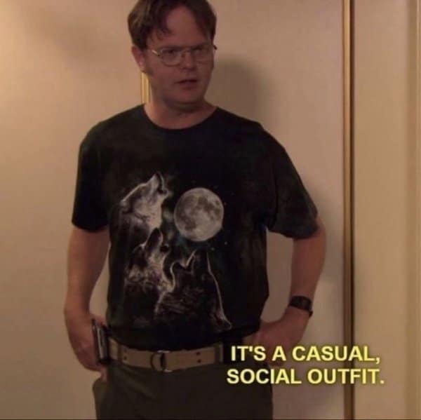 A classic meme from The Office featuring Dwight Schrute wearing the legendary "Three Wolf Moon" t-shirt. The yellow subtitle captures his confident logic: "IT'S A CASUAL, SOCIAL OUTFIT."