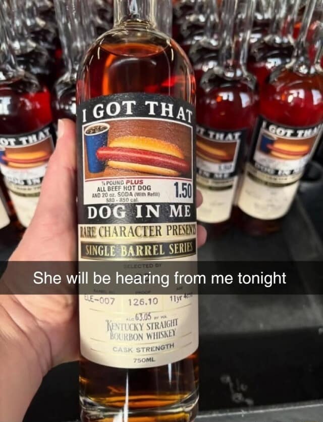 A "Got that dog in me" classic meme featuring a hand holding a bottle of bourbon with a custom label showing the iconic $1.50 Costco hot dog and soda combo. The Snapchat caption warns: "She will be hearing from me tonight."