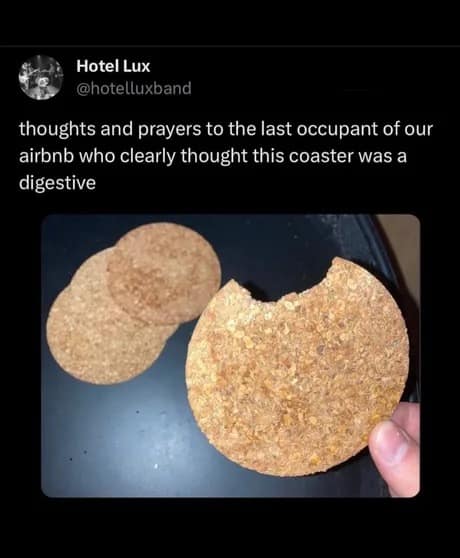 A "cursed" classic meme tweet from the band Hotel Lux showing a close-up of a circular cork coaster with a large, human-sized bite taken out of it. The caption offers "thoughts and prayers" to the previous Airbnb guest who mistook the cork for a digestive biscuit.
