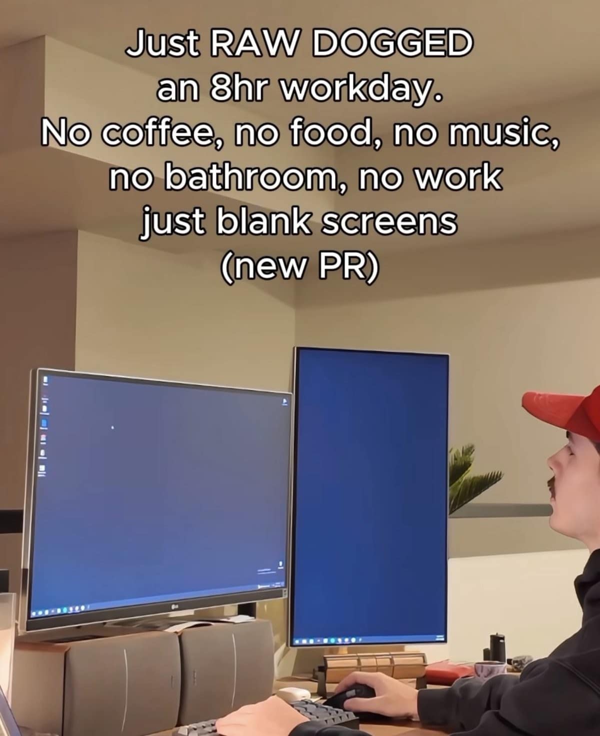 A modern classic meme showing a man with a mustache and a red cap sitting at a high-end desk. He is staring intensely at two vertical, completely blank blue computer screens. The text claims he is "RAW DOGGING" an 8-hour workday with no coffee, food, music, or actual work—just staring at the void to set a "new PR."