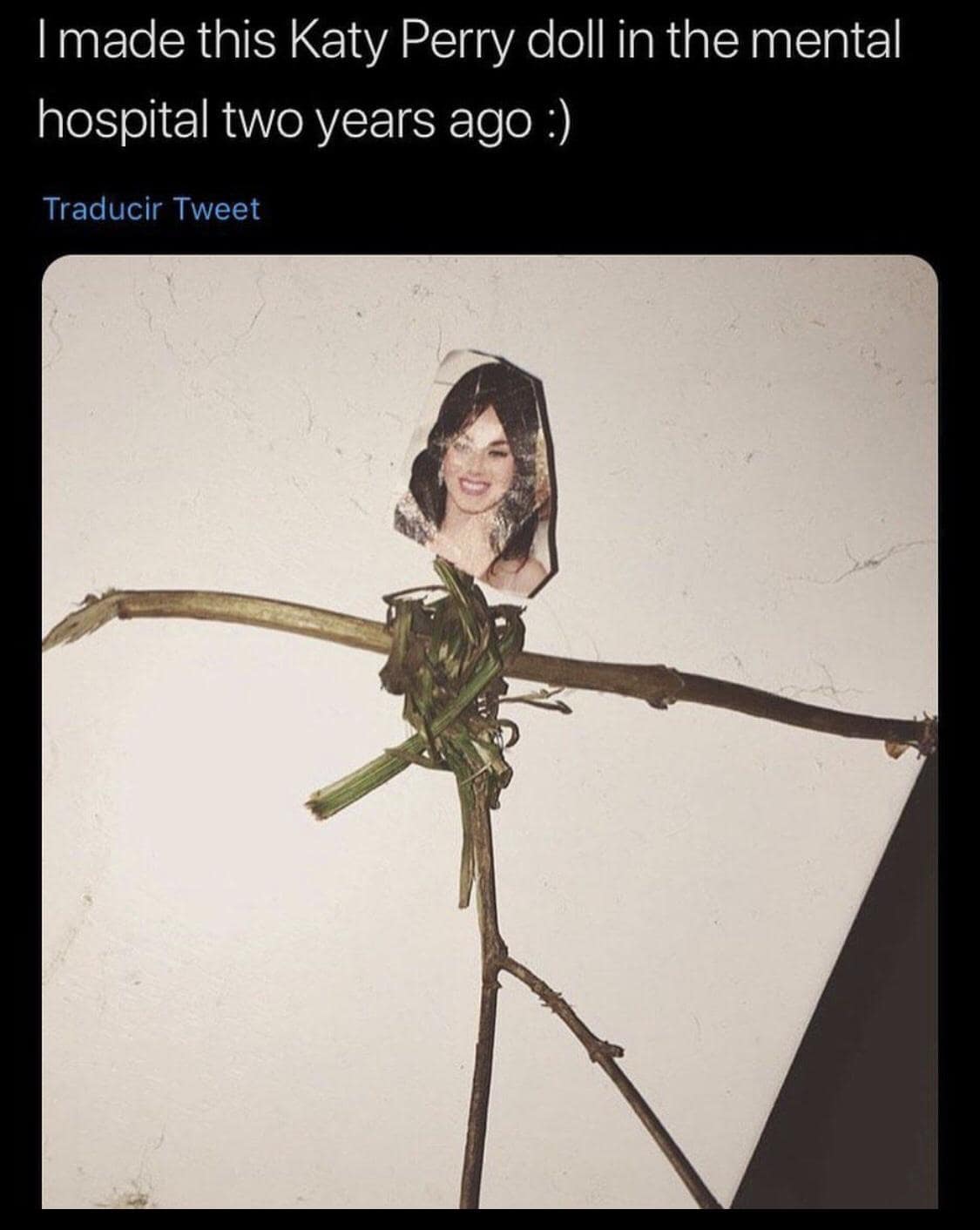 A weird and unsettling classic meme showing a crude doll made of twigs and grass with a cutout of Katy Perry's face taped to the top. The caption reads: "I made this Katy Perry doll in the mental hospital two years ago :)."