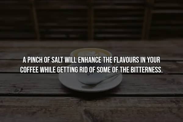 White cup and saucer on weathered wooden table, demonstrating salt-in-coffee hack to reduce bitterness.