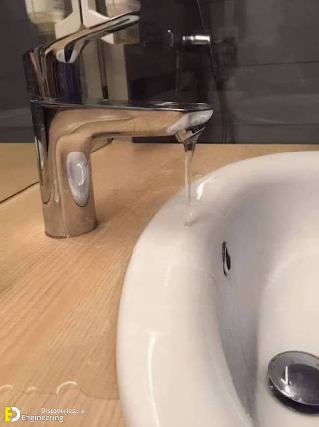 Bathroom faucet installed too close to sink edge causing water to pour directly onto wooden counter