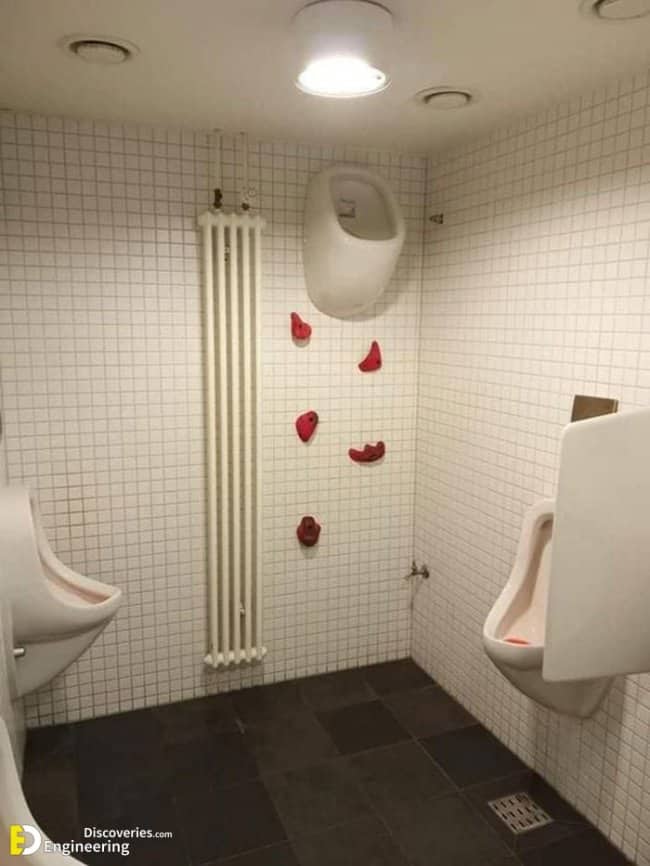 Urinal mounted impossibly high on bathroom wall with rock climbing holds required to reach it