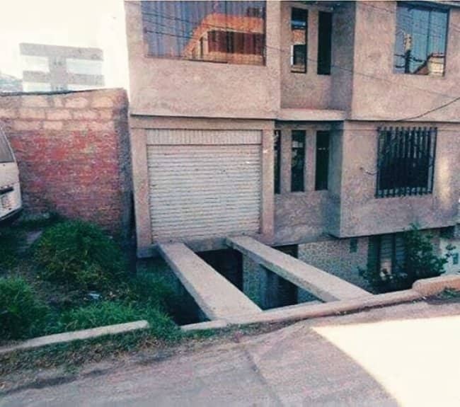 Residential garage door opens over a deep open pit trench with no driveway access below