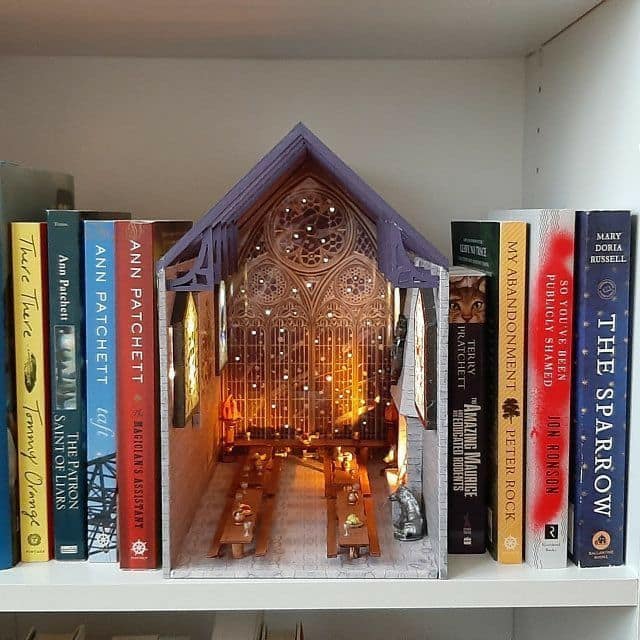 Majestic gothic great hall cool bookends showcasing miniature banquet tables and a detailed stone-etched rose window glowing from within the shelf.