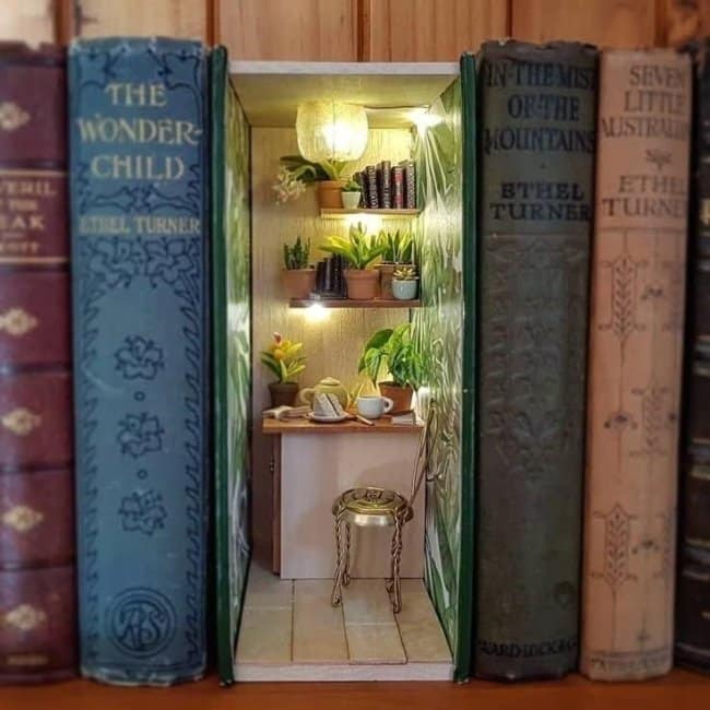 Airy botanical nook cool bookends featuring miniature shelves of green succulents, a white brick wall, and a gold stool beside a tiny cup of tea.