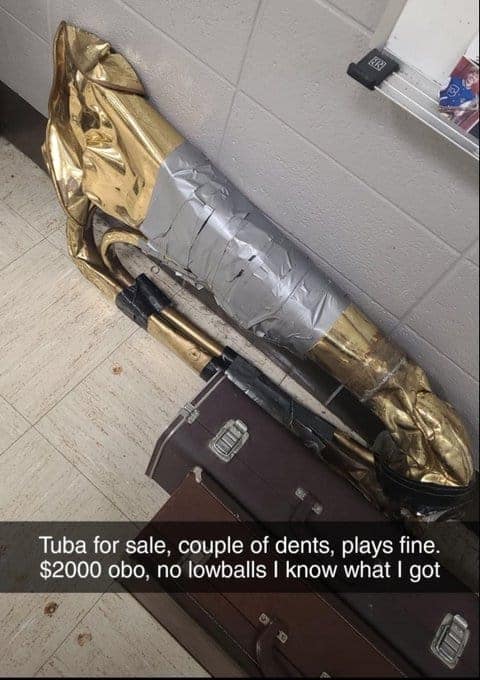 A hilarious cursed instrument Marketplace ad for a tuba that has been completely crushed, flattened, and "repaired" with massive amounts of silver duct tape. The caption reads: "Tuba for sale, couple of dents, plays fine. $2000 obo, no lowballs I know what I got."