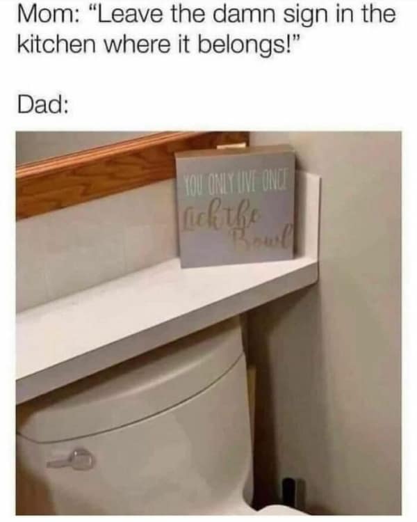 A domestic subversion meme showing a decorative wooden sign that reads "You Only Live Once, Lick the Bowl." While intended for the kitchen, the dad has moved it to the shelf directly above the toilet tank to spite the mother’s interior design choices.
