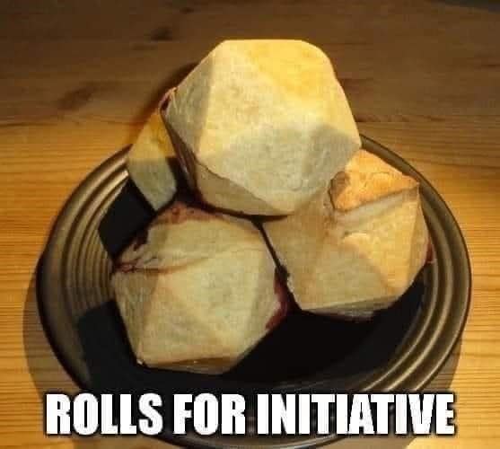 A d&d meme featuring a close-up of a wooden bowl filled with baked bread rolls shaped into perfect twenty-sided dice. The bottom text reads "ROLLS FOR INITIATIVE."